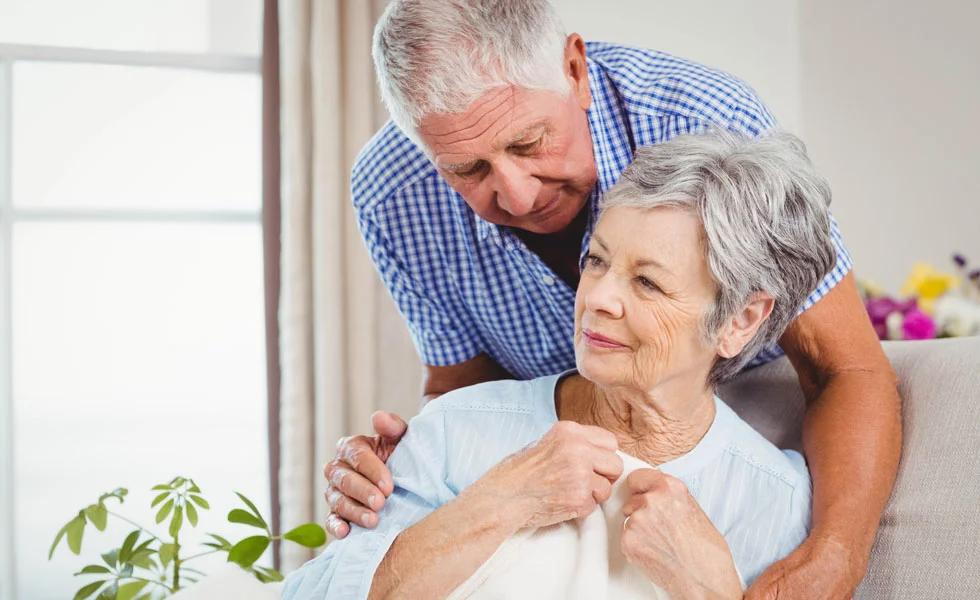 An older couple, the husband consoles his wife who is sitting down