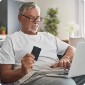 Man holding credit card while typing on laptop