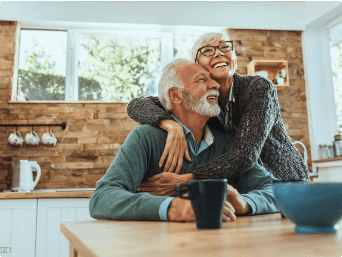 Elderly couple smiling and hugging each other in their kitchen