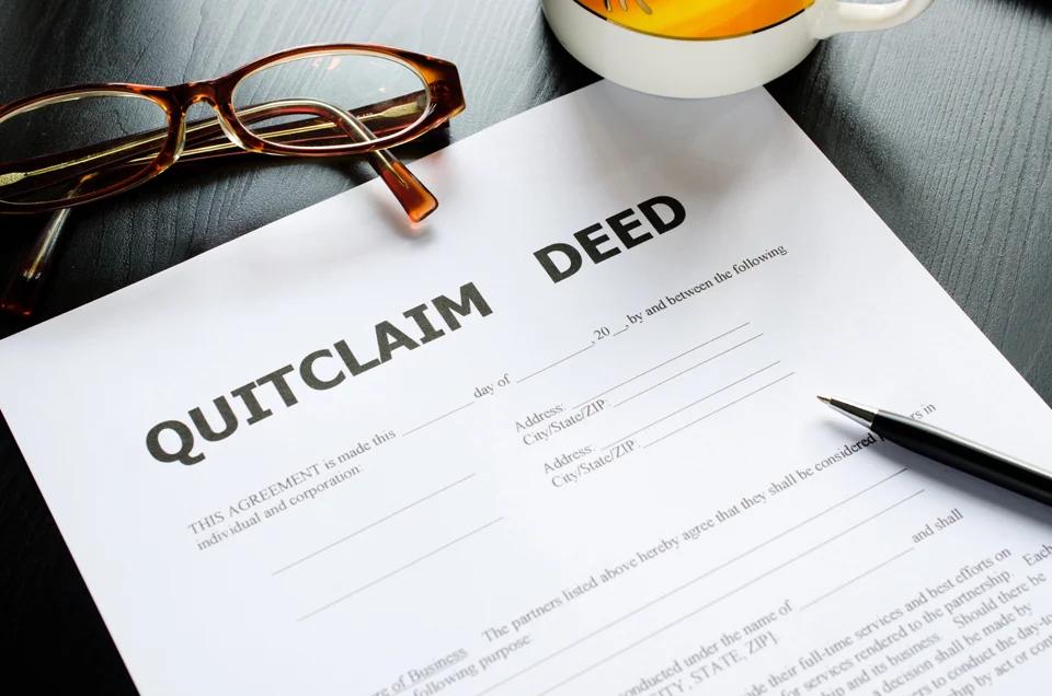 A paper on a desk that is titled Quitclaim Deed with a pen on top of it.